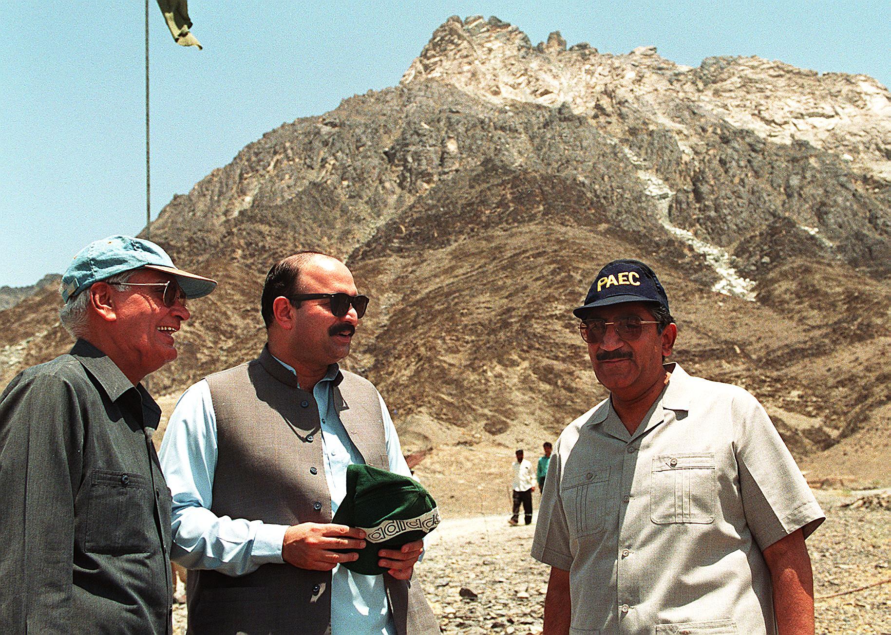 Pakistan's prominent scientists Dr. Samar Mubarak (R) and Dr. Ishfaq Ahmed (L), chairman of country's Atomic Energy Commission, stands in front of a hill under which Pakistan conducted its five nuclear tests, along with minister of information Mushahid Hussain, 29 June. 
